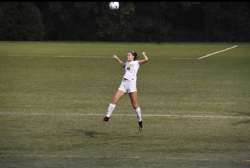 Ella Luter striking a header to redirect the ball from the goal.